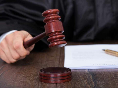 Judge striking gavel near documents and pen.