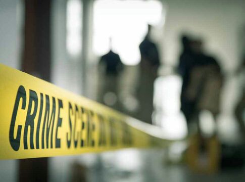 Crime scene tape with people in the background.